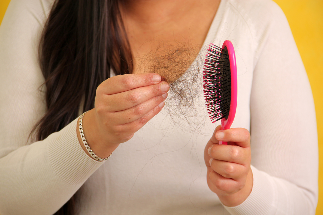 Latin adult woman with very long straight hair suffers from hair loss looking at the brush how many hairs fall out in one brush due to illness